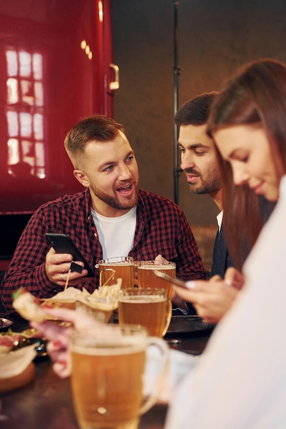 Fim de semana passando Grupo de jovens amigos sentados juntos no bar com cerveja