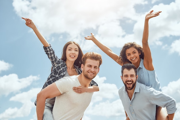 Fim de semana perfeito juntos dois jovens casais se divertindo ao ar livre mulheres sentadas nas costas de