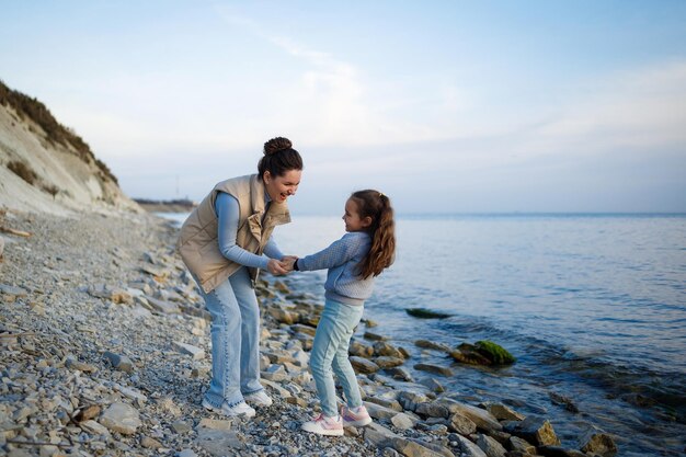 Foto fin de semana familiar junto al mar feliz madre e hija se divierten en un paseo puesta de sol en el mar