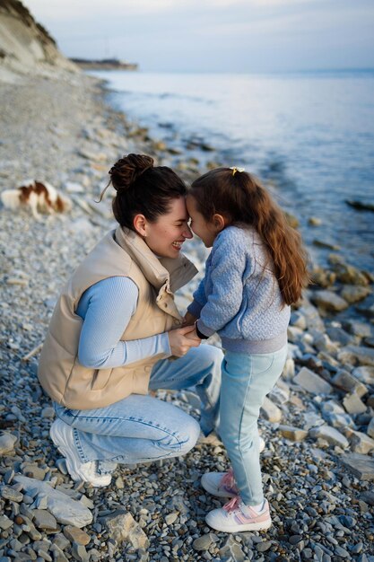 Foto fin de semana familiar junto al mar feliz madre e hija se divierten en un paseo puesta de sol en el mar