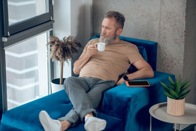 Fin de semana. Un hombre tomando su café de la mañana y luciendo relajado.