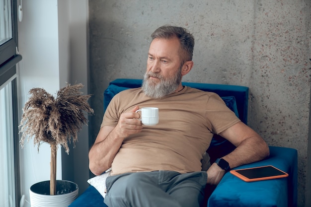 Fin de semana. Un hombre tomando su café de la mañana y luciendo relajado.