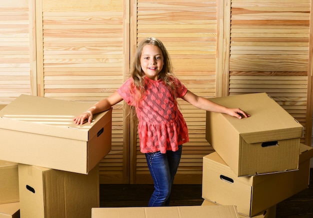 Finalmente criança feliz caixa de papelão compra de nova habitação Caixas de papelão se mudando para uma nova casa conserto de quarto novo apartamento desembalando caixas de mudança menina feliz sente-se no quarto em caixas