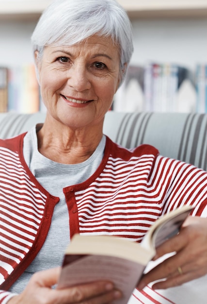 Finalmente tenho tempo para trabalhar na minha lista de leitura obrigatória Uma mulher idosa sorrindo para a câmera enquanto relaxa com um livro