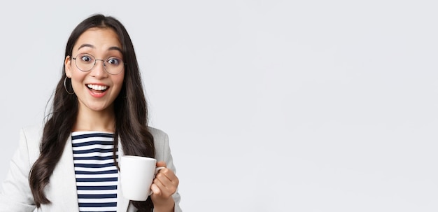 Finanças de negócios e emprego conceito de empreendedores bem-sucedidos femininos Closeup de trabalhador de escritório asiático sorridente de saída falando com colega de trabalho na cozinha do escritório bebendo café