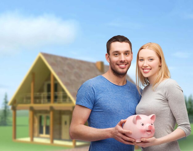 Finanças, dinheiro e conceito de família - casal sorridente segurando o grande cofrinho