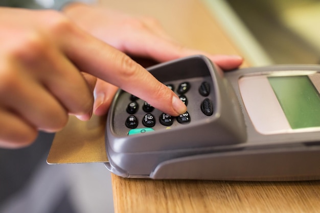 finanças, dinheiro, tecnologia, pagamento e conceito de pessoas - close-up da mão inserindo código pin para o terminal de leitor de cartões