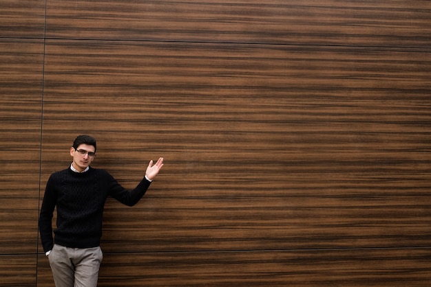 Finanças empresariais. trabalhador de escritório confiante. homem de estilo casual mostrando algo com um gesto de mão. propaganda. fundo de parede de textura de madeira. rua ao ar livre. copie o conceito de espaço