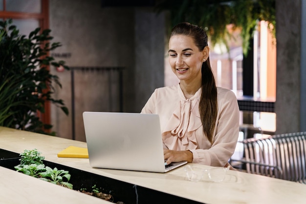 Una financiera trabaja en una oficina de coworking. Un programador humano usa una computadora portátil para comunicarse.