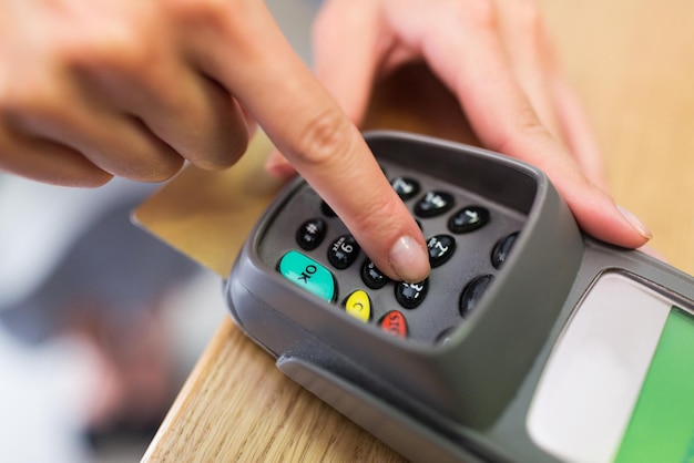 Finanz-, Geld-, Technologie-, Zahlungs- und Menschenkonzept - Handansicht bei der Eingabe des PIN-Codes an einem Kartenleser-Terminal