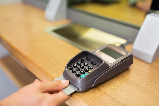 Foto finanzas, dinero, tecnología, pago y concepto de personas: cerca de la mano que inserta la tarjeta bancaria en la terminal