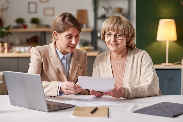 Finanzberater bespricht zusammen mit einer älteren Frau ein Testament, während sie zu Hause ein Meeting haben