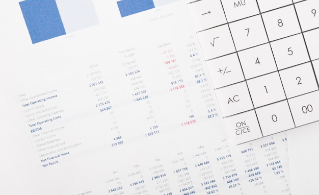 Finanzdiagramme und ein Taschenrechner auf dem Schreibtisch des Buchhalters. Berechnung von Gewinnen, Steuern und Bezahlung der Gehälter von Mitarbeitern.