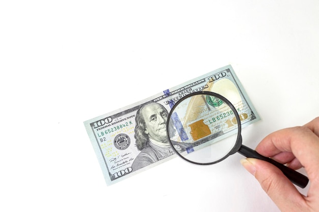 Finanzen und Wirtschaft Nahaufnahmefoto mit einer Lupe über 100-Dollar-Banknoten