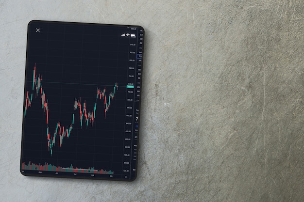 Finanzmarktdiagramm auf dem Tablet-Bildschirm auf Zementhintergrund. Ansicht von oben. Börse.