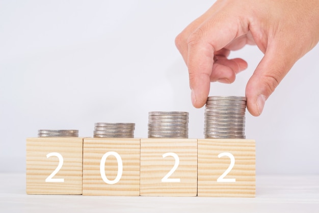 Finanzplan für 2022. Rk legt Münzen in Stapel auf Holzwürfeln, Budgetplanungskonzept.