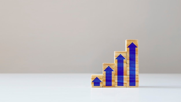 Finanzwachstumskonzept und Holzwürfel mit Pfeilsymbol, das ständig zunimmt