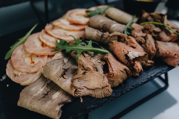 Finas rodajas de carne, jamón, tocino se encuentran en un plato blanco. La carne se planta en palillos de dientes, muestras de productos para analizar.