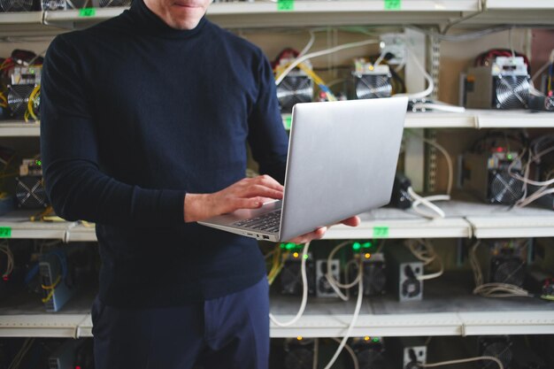 Finca con equipo para minería de criptomonedas bitcoin. Hombre de negocios, posición, con, computador portatil