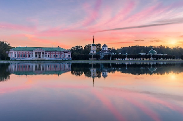 Finca de Kuskovo y reflejo en el estanque. Parque Kuskovo: palacio, campanario y estanque en el colorido amanecer rosado soleado. Moscú, Rusia