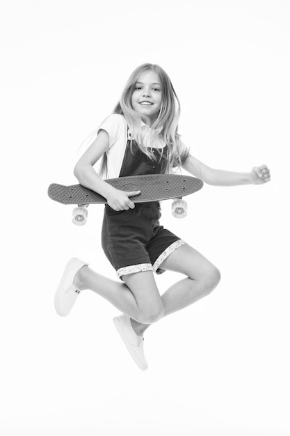 Finden Sie Ihre Freiheit Kleines Mädchen springen mit Skateboard, isoliert auf weiss Kind Skater Lächeln mit Longboard Skateboard Kind in rosa Overall Sportliche Aktivität und Energie Kindheit und aktive Spiele