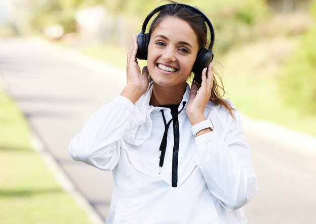 Finden Sie Ihre Strecke und rennen Sie dorthin Zugeschnittenes Porträt einer attraktiven und sportlichen jungen Frau, die Musik hört, während sie im Freien steht