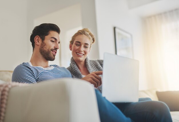 Los fines de semana como deberían ser Foto de una pareja joven usando una computadora portátil en el sofá de su casa