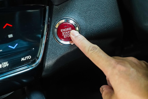 Finger, der den Motor-Start-Stopp-Knopf eines Autos drückt