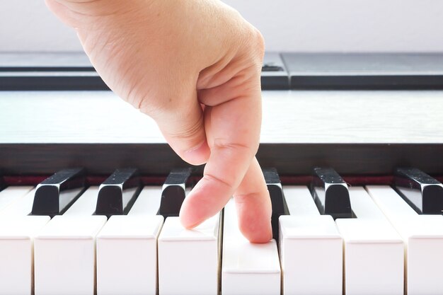 Finger der Frau, der auf Klaviertaste zeigt.