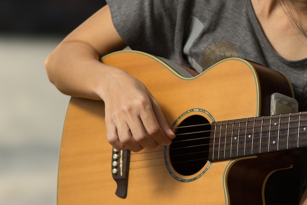 Finger des Mädchens spielen Gitarre im Park