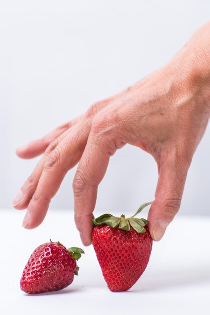 Finger, die einen gesunden lebenden Lebensstil der roten Erdbeerfrucht wählen