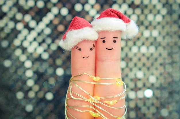 Fingerkunst des Paares feiert Weihnachten. Konzept von Mann und Frau, die in Hüten des neuen Jahres lachen.