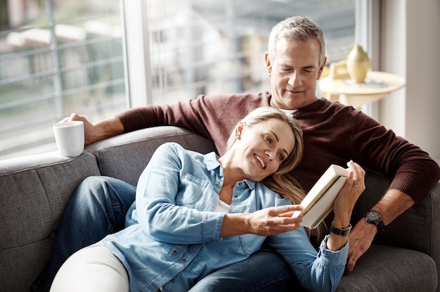 Fins de semana foram feitos para relaxar foto de um casal maduro lendo um livro juntos enquanto relaxa no sofá em casa