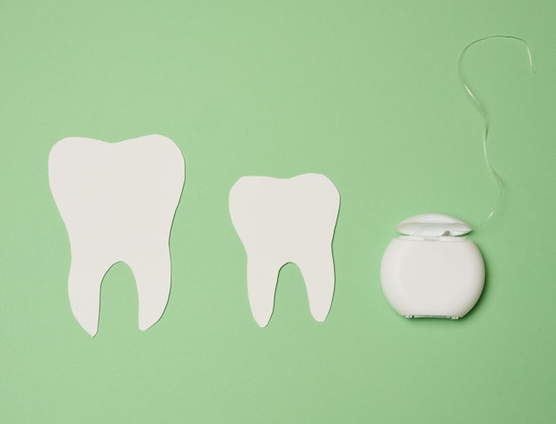 Fio dental e dentes de papel em fundo verde higiene bucal