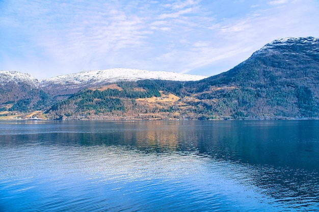 Fiorde com montanhas cobertas de neve no horizonte A água brilha na Noruega