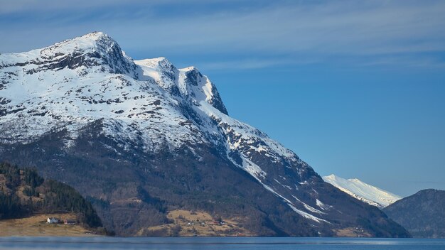 Fiordo con montaña cubierta de nieve en el horizonte El agua brilla en el paisaje de Noruega