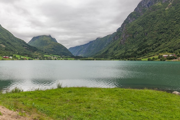 Fiordo noruego y montañas rodeadas de nubes, reflejo del fiordo ideal en agua clara