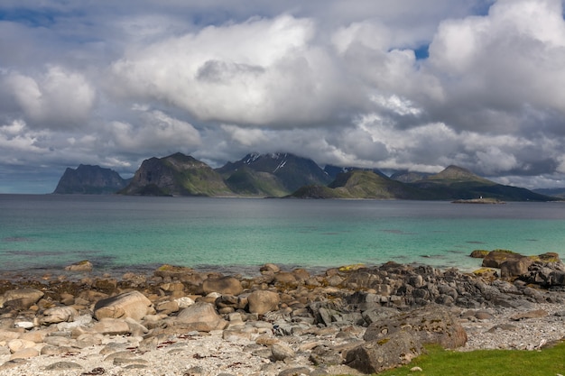 Fiordo noruego y montañas rodeadas de nubes, reflejo del fiordo ideal en agua clara