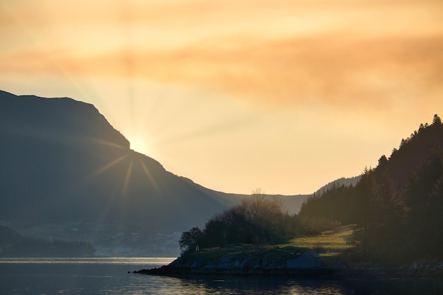 Fiordo con vistas a las montañas en Noruega El sol se pone detrás de la montaña