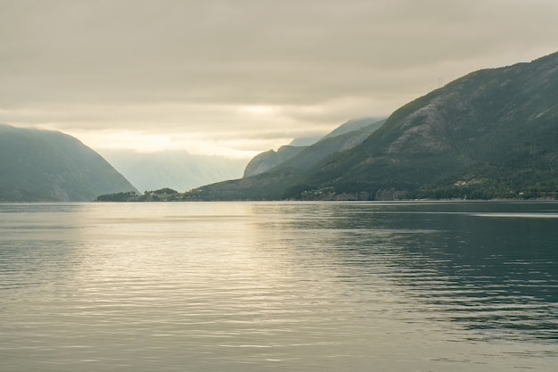 Fiordos noruegos mar niebla puesta de sol paisaje de montaña, Noruega.