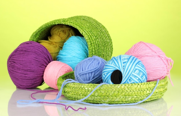 Fios coloridos para tricotar em cesto verde sobre fundo verde