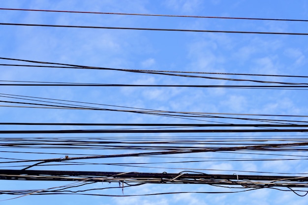 Fios elétricos e linha telefônica contra o céu azul