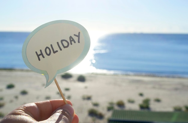 Fique com o balão de papel com as palavras Holiday no fundo do mar azul