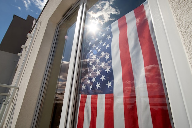 Fique em casa. Bandeira americana na janela da casa.