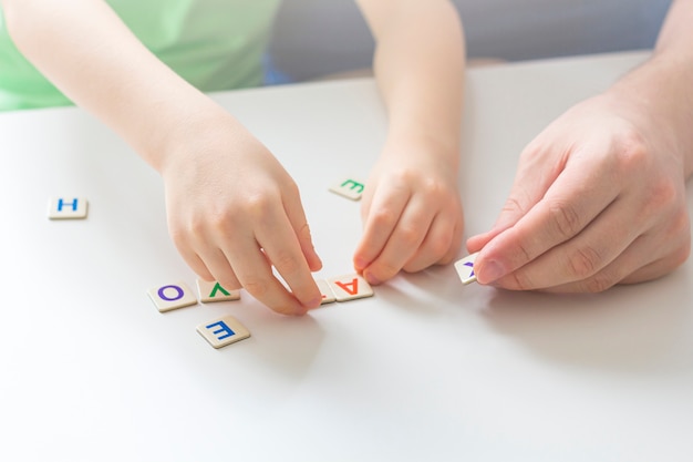 Fique em casa, distância social e auto-isolamento durante o conceito de quarentena. Lazer em família. Pai e filho jogando jogos de lógica e quebra-cabeças de madeira.