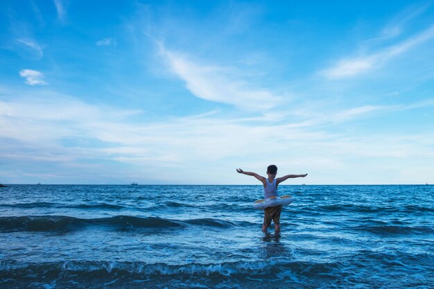 Foto fique forte. o menino de pé no meio das ondas do mar