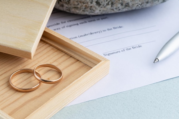 Firma de contrato de matrimonio forma acuerdo con un par de anillos de boda