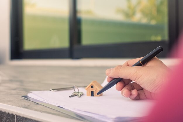 Foto firmando a mano un contrato de compra de una casa