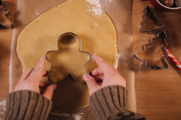 First-Person-Ansicht einer Frau, die zu Hause Lebkuchen macht, weibliche Kekse aus Lebkuchenteig schneiden