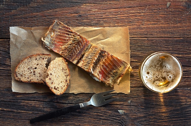 Fisch auf einem Papier mit Brot und Glas Bier